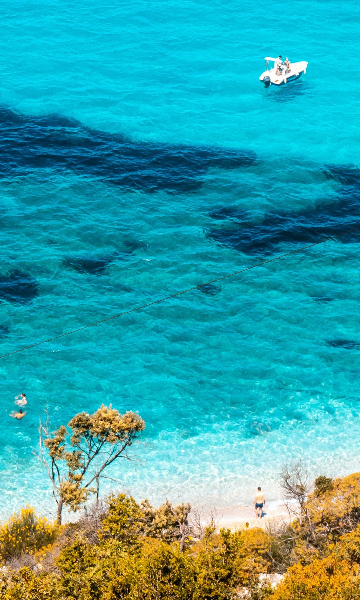Klares Wasser der Bucht von Pulëbardha bei Ksamil, gerahmt von bewachsenen Hängen